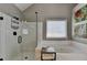 A main bathroom featuring a glass shower, soaking tub, white tiling, and two floral wall decorations at 4770 Spring Park Cir, Suwanee, GA 30024