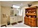 Bright bathroom featuring double vanity, a skylight, and furniture-style shelving at 4853 Carlene Sw Way, Lilburn, GA 30047