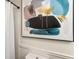 Close-up of a toilet and shower with a white curtain and colorful artwork on the wall at 215 Ansley Ct, Roswell, GA 30076