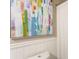 Close-up of a toilet and shower with a white curtain and colorful artwork on the wall at 215 Ansley Ct, Roswell, GA 30076