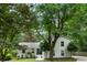 Picturesque two-story home surrounded by mature trees, featuring a well-manicured front yard and classic architectural details at 215 Ansley Ct, Roswell, GA 30076
