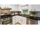 Bright kitchen with stainless appliances, white cabinetry, tile backsplash, and granite counters at 215 Ansley Ct, Roswell, GA 30076