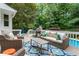 Pool deck features an outdoor grill, cushioned seating, a blue umbrella, and shade trees at 215 Ansley Ct, Roswell, GA 30076