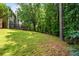 Backyard with green grass and wooded area and a wood deck, creating a serene outdoor environment at 496 Bottesford Nw Dr, Kennesaw, GA 30144