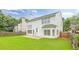 View of a fenced backyard with green lawn, a patio, and the rear elevation of the house with many windows at 2011 Wildcat Lake Ct, Lawrenceville, GA 30043