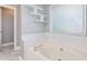 Close up of tiled tub, showing decorative white shelves, tile detail, and bright window light at 3554 Cherry Blossom Court, Loganville, GA 30052