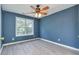 This bedroom features beautiful, blue walls, light wood floors, a window, and a ceiling fan with lights at 3554 Cherry Blossom Court, Loganville, GA 30052