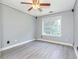 This bedroom features neutral-painted walls, light wood floors, a window, and a ceiling fan with lights at 3554 Cherry Blossom Court, Loganville, GA 30052