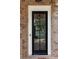 Entryway featuring a black front door with glass panels, brickwork, and a smart lock at 904 Urban Ash Ct, Johns Creek, GA 30022