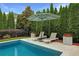 Relaxing backyard pool with lounge chairs, umbrella, and manicured shrubs at 904 Urban Ash Ct, Johns Creek, GA 30022