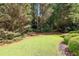 Well-maintained backyard featuring manicured lawn and mature trees at 13995 Mariners Cv, Alpharetta, GA 30005