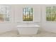 Bright bathroom features a freestanding tub with window views and white shutters at 2410 Glade Overlook, Cumming, GA 30041