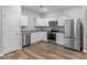 Modern kitchen boasts stainless steel appliances, white cabinetry, granite countertops, and wood-look flooring at 3135 Journal Ct, Decatur, GA 30035