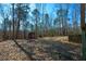 Backyard view featuring lush greenery, an outbuilding, and a retaining wall at 6865 Cowan Mill Rd, Winston, GA 30187