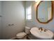 Cozy half-bath featuring a pedestal sink, toilet, framed mirror, and window at 6865 Cowan Mill Rd, Winston, GA 30187
