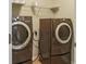 This laundry room features modern, front-load washer and dryer, complemented by overhead shelving for optimal storage at 2638 Lake Manor Cir, Duluth, GA 30096