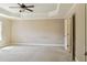 Spacious primary bedroom with tray ceiling, fan, neutral walls, and carpet; inviting and serene at 2638 Lake Manor Cir, Duluth, GA 30096