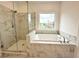 Bright bathroom featuring soaking tub, glass shower, and serene outdoor view at 500 Healy Dr # 77, Cumming, GA 30040