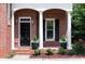 Inviting front porch with brick columns and classic black door with flower planters on either side at 1560 Heritage Trl, Roswell, GA 30075