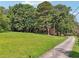 Lush front yard with a long driveway leading to a charming house, surrounded by mature trees and greenery at 3657 Linda Dr, Loganville, GA 30052