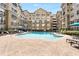 Large community pool surrounded by lounge chairs, umbrellas, and lush landscaping and apartments in the background at 800 Peachtree Ne St # 8612, Atlanta, GA 30308