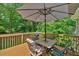 A wooden back deck featuring patio table with umbrella and seating surrounded by a wooded background at 323 Bells Ferry Ne Rd, White, GA 30184
