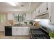Well-lit kitchen with white cabinets, stainless appliances, and garden window at 3087 Drexel Ln, Jonesboro, GA 30236