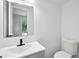 Well-lit bathroom with a sleek, wall-mounted mirror and vanity, complete with a white toilet and black faucet at 4148 Emerald North Dr, Decatur, GA 30035