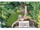 Aerial shot of a backyard featuring a stone patio with fire pit, lush lawn, and extensive landscaping at 660 Briarleigh Way, Woodstock, GA 30189