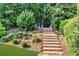 Landscaped backyard featuring wood steps leading to an upper tier with lounge chairs at 660 Briarleigh Way, Woodstock, GA 30189