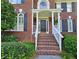 Close up of a red brick house entrance with white columns, black door, brick steps and green bushes at 1620 Silverleaf Way, Alpharetta, GA 30005