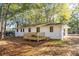 Rear view of house with a new deck, windows with black trim, and surrounded by mature trees at 409 Colette Ln, Social Circle, GA 30025