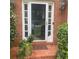Inviting front door with glass panel and sidelights, adorned with plants and brick walkway at 1884 Whitehawk Ct, Lawrenceville, GA 30043