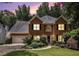 Charming brick two-story home featuring a well-manicured lawn and attached two-car garage at dusk at 1884 Whitehawk Ct, Lawrenceville, GA 30043