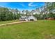 Two-story white farmhouse with black trim and wood shutters surrounded by a green lawn and woods at 3088 Hiram Sudie Road, Hiram, GA 30141