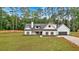 Charming two-story white farmhouse with black trim and wood shutters surrounded by green lawn and woods at 3088 Hiram Sudie Road, Hiram, GA 30141