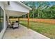 A covered patio with a dining set and grill overlooking a spacious backyard with a wooden fence and lush greenery at 3088 Hiram Sudie Road, Hiram, GA 30141