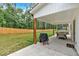 A covered patio with a dining set and grill overlooking a spacious backyard with a wooden fence and lush greenery at 3088 Hiram Sudie Road, Hiram, GA 30141
