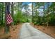 Long concrete driveway leading through a wooded area with an American flag draped on a tree at 188 Macedonia Rd, White, GA 30184