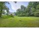 Expansive grassy backyard featuring mature trees and a brick house with a walk out basement, offering serene privacy at 4829 Moon Rd, Powder Springs, GA 30127