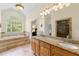 Bright bathroom featuring dual vanities, granite countertops, a soaking tub with a large window and glass shower at 4829 Moon Rd, Powder Springs, GA 30127