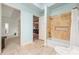 Bathroom featuring a bathtub and shower, complemented by travertine tile and plenty of natural light at 4829 Moon Rd, Powder Springs, GA 30127