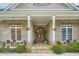 Inviting porch featuring double wood doors with arched glass, surrounded by brickwork, stone accents, and potted plants at 4829 Moon Rd, Powder Springs, GA 30127