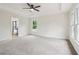 Main bedroom with a ceiling fan, light gray carpet and views to the yard and en-suite bath at 9744 Spyglass Dr, Villa Rica, GA 30180