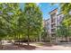 Attractive condo building exterior with trees and benches in a courtyard setting on a sunny day at 390 17Th Nw St # 6055, Atlanta, GA 30363