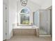 Bright bathroom featuring a soaking tub, shower, and large window at 4050 Bonnett Creek Ln, Hoschton, GA 30548