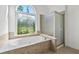 Bathroom features a soaking tub, shower, and a decorative window at 4050 Bonnett Creek Ln, Hoschton, GA 30548