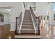 Grand staircase with dark wood railing and decorative iron spindles in a brightly lit, open floor plan home at 4050 Bonnett Creek Ln, Hoschton, GA 30548