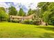 Lush backyard with a sprawling lawn, mature trees, and a charming two-story house at 130 Brooklet Way, Brooks, GA 30205