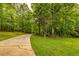 Scenic view of a winding driveway leading to a wooded property with lush green grass at 130 Brooklet Way, Brooks, GA 30205